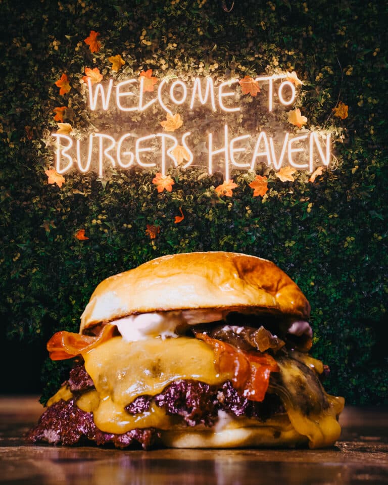 Hamburguesa fotografiada ante un rótulo de neón en el local