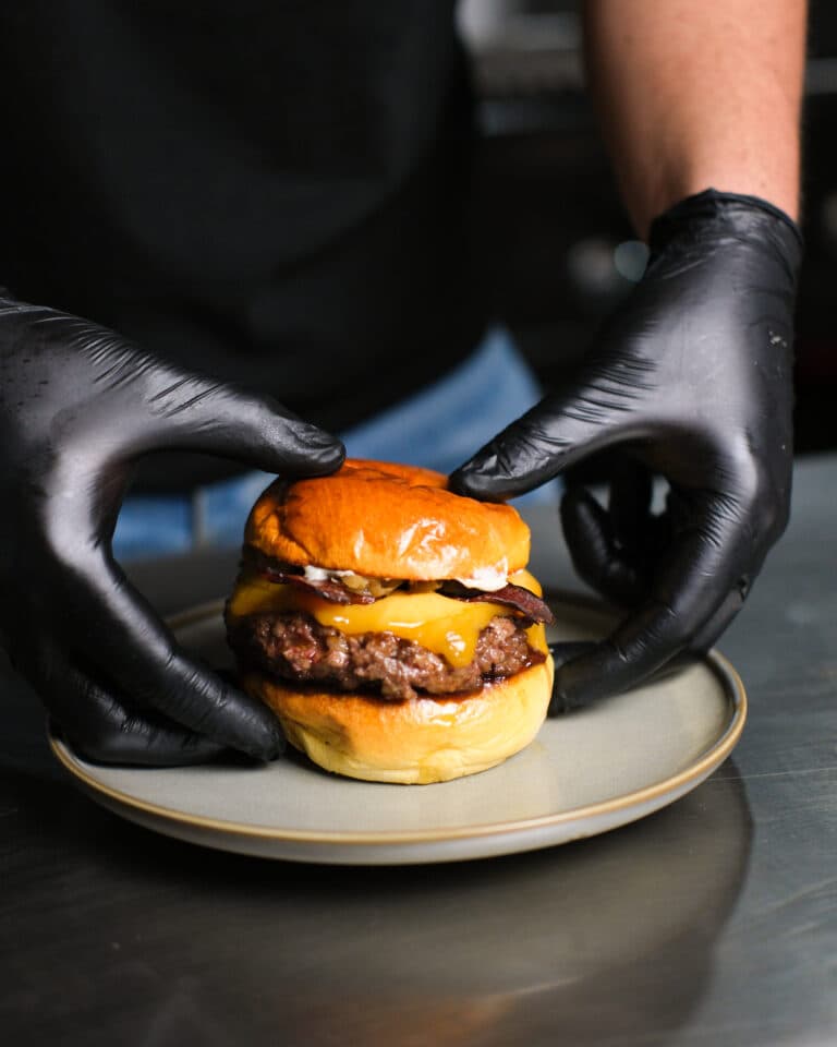 Mans amb guant emplatant una hamburguesa a la cuina